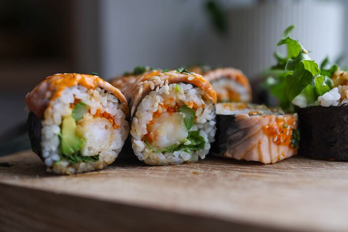 A close up shot of various freshly made sushi rolls, showcasing people behaving like they are owed everything