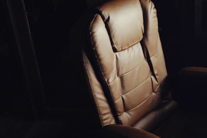 A close-up of a plush passenger seat on a bus, showing how people behaving like the world owed them everything take up space.