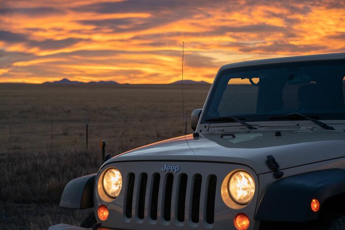 A Jeep with headlights on at sunset, capturing journeys where people behaved like the world owed them everything.