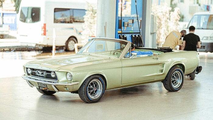 Vintage green convertible car parked at a gas station, reflecting on people behaving like the world owed them everything