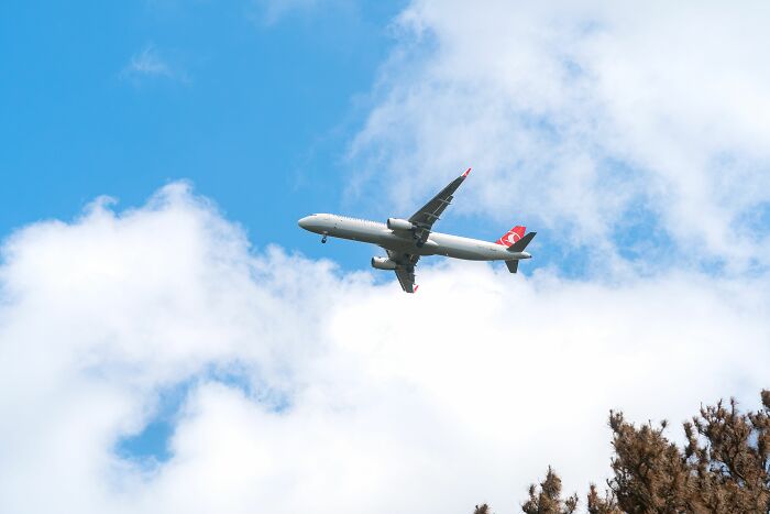Turkish Airlines airplane flying high in the blue sky with clouds, highlighting experiences of people behaving entitled