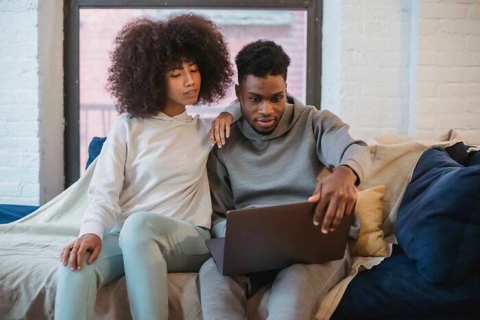 Couple sitting on couch looking at laptop screen together