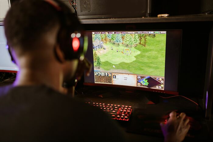 Person playing strategy game on computer with headset