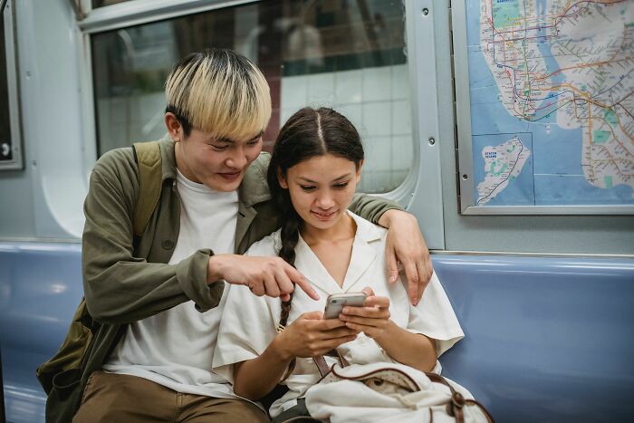 Couple looking at phone together on subway train