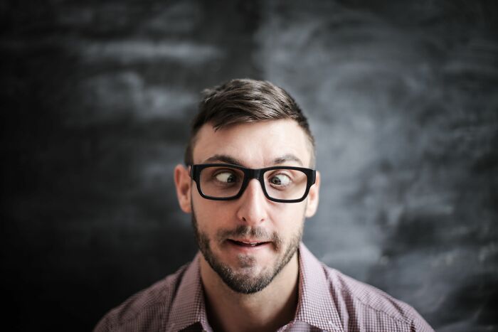 Man with glasses making a funny face in front of blackboard