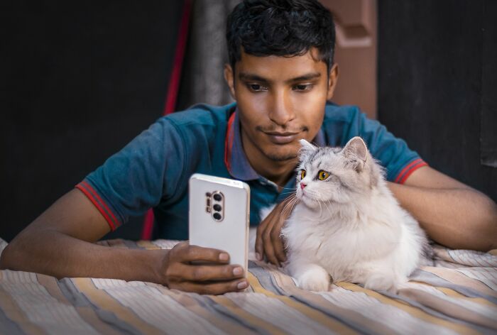 Man with smartphone and white cat lying on bed illustrating unexpected BF phone finds