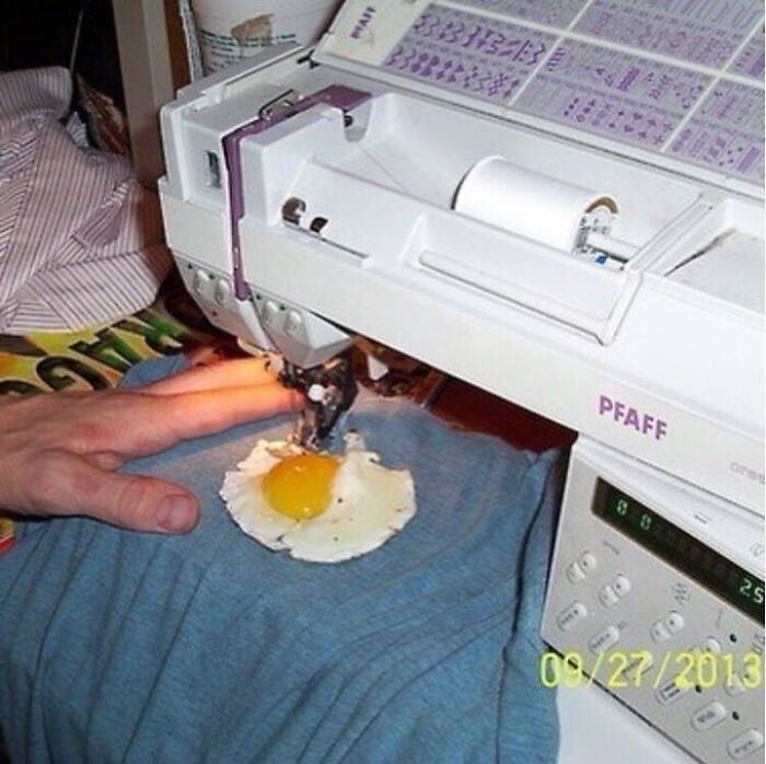 Sewing machine stitching a fried egg on blue fabric in a strange cursed image