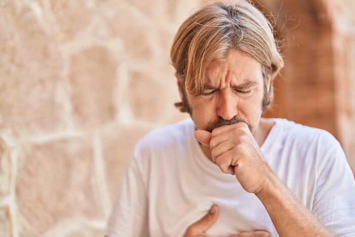 Man coughing and clutching chest depicting health reactions