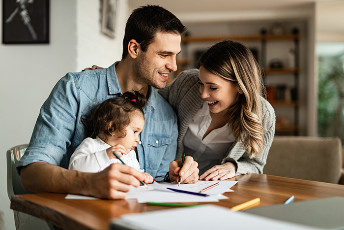 Smiling dad boasts about his parenting while coloring with his happy family at a table Smiling dad boasts about his parenting while coloring with his happy family at a table