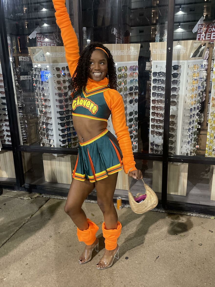 Woman in a green and orange cheerleading uniform posing, showcasing creative Halloween costume ideas.